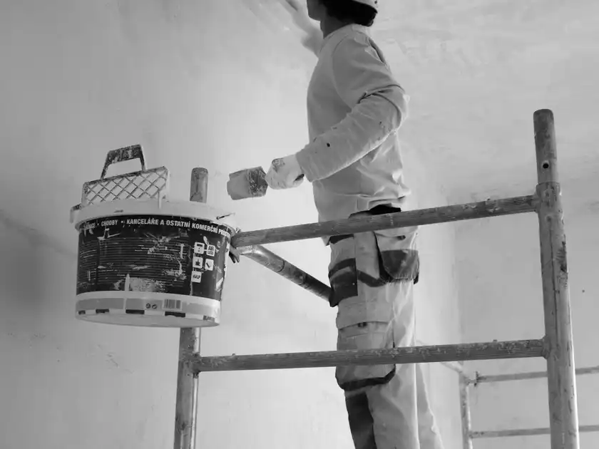 A painter on a scaffold painting an interior wall